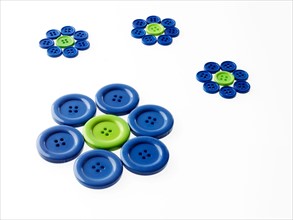 Studio shot of blue and green buttons arranged in flower head. Photo : David Arky