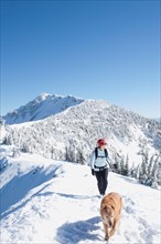 USA, Montana, Bob Marshall Wilderness, Mt.Aeneus. Woman hiking with her dog in winter scenery.
