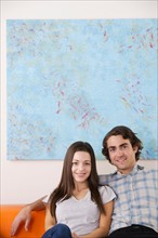 Portrait of young couple sitting on sofa. Photo : Rob Lewine