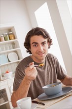 Portrait of young man eating breakfast. Photo : Rob Lewine