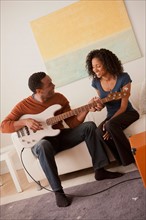 Man playing electric guitar to his girlfriend. Photo : Rob Lewine