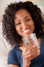 Portrait of smiling woman holding glass of water. Photo : Rob Lewine