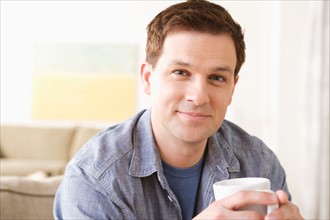 Portrait of smiling mid adult man holding mug. Photo : Rob Lewine