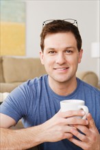 Portrait of smiling mid adult man holding mug. Photo : Rob Lewine