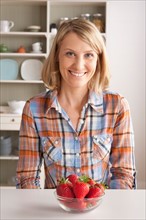 Portrait of mid adult woman with bowl of strawberries. Photo : Rob Lewine