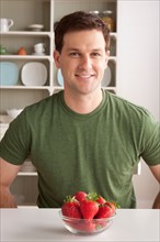 Portrait of mid adult man with bowl of strawberries. Photo : Rob Lewine