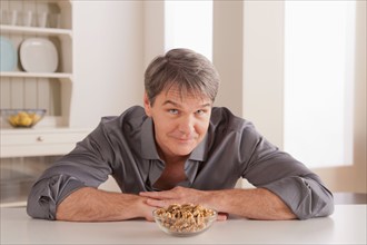 Portrait of mature man with snacks on table. Photo : Rob Lewine