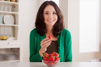 Portrait of mature woman with strawberries on table. Photo : Rob Lewine