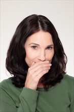 Studio portrait of mature woman covering mouth. Photo : Rob Lewine