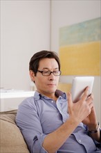 Man reading e-book at home. Photo : Rob Lewine