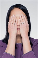 Studio portrait of mature woman covering eyes. Photo : Rob Lewine