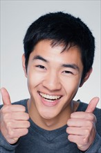 Studio portrait of young man showing thumbs up sign. Photo : Rob Lewine
