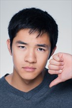 Studio portrait of young man showing thumbs down sign. Photo : Rob Lewine