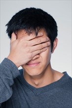 Studio portrait of young man covering eyes. Photo : Rob Lewine