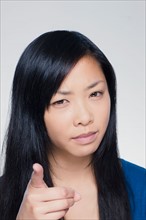 Studio portrait of young woman pointing finger. Photo : Rob Lewine