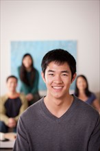 Portrait of young man with family in background. Photo : Rob Lewine