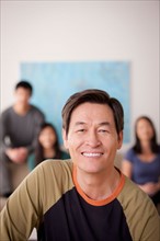 Portrait of mature man with family in background. Photo : Rob Lewine