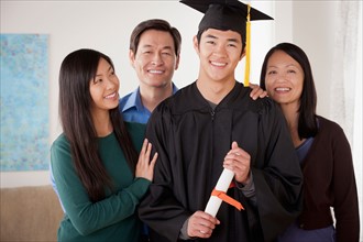 Portrait of young man in graduation gown with family. Photo : Rob Lewine