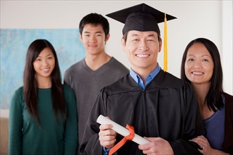 Portrait of mature man in graduation gown with family. Photo : Rob Lewine