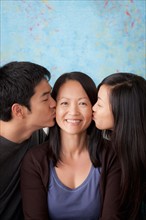 Smiling mother kissed by her children. Photo : Rob Lewine