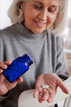 Senior woman holding medicine bottle. Photo : Rob Lewine