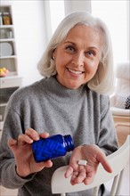 Senior woman holding medicine bottle. Photo : Rob Lewine