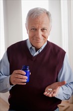 Senior man holding medicine bottle. Photo : Rob Lewine