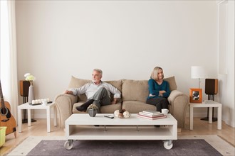Angry senior couple sitting on sofa. Photo : Rob Lewine