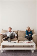 Angry senior couple sitting on sofa. Photo : Rob Lewine
