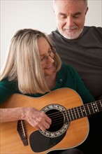 Senior couple, woman playing guitar. Photo : Rob Lewine