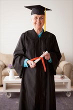 Senior woman wearing graduation gown. Photo : Rob Lewine