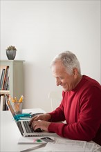 Senior man using laptop. Photo : Rob Lewine
