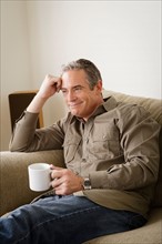 Smiling mature man holding mug. Photo : Rob Lewine