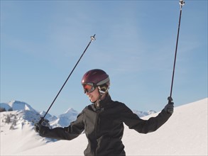 Austria, Maria Alm. Young woman in ski gear at top of mountain. Photo : Mark de Leeuw