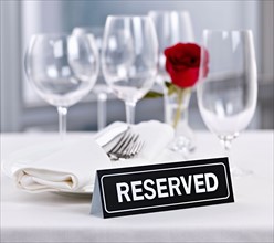 Dishes and cutlery prepared for meal in restaurant with reserved sign. Photo : Elena Elisseeva
