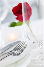 Dishes and cutlery prepared for meal decorated with red rose. Photo : Elena Elisseeva