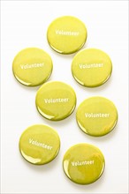 Close-up studio shot of yellow volunteer badges on white background. Photo : Elena Elisseeva