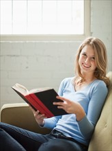 Indoor portrait of young attractive woman sitting with book. Photo : Jessica Peterson