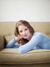 Indoor portrait of young attractive woman reclining on sofa. Photo : Jessica Peterson
