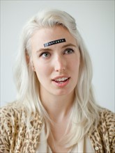 Portrait of confused young woman with black label on forehead. Photo : Jessica Peterson