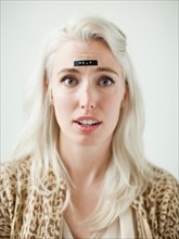 Portrait of young woman with word help on forehead. Photo : Jessica Peterson