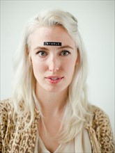 Portrait of young woman with word single on forehead. Photo : Jessica Peterson