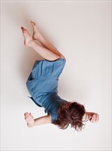 Young woman wearing blue dress falling upside down. Photo : Jessica Peterson