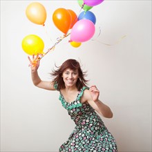Attractive young woman playing with colorful balloons. Photo : Jessica Peterson