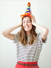 Studio shot of young woman wearing party hat. Photo : Jessica Peterson