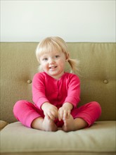 Portrait of baby girl (18-23 months) sitting on sofa. Photo : Jessica Peterson