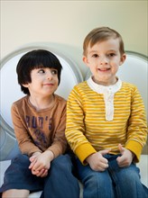Studio Shot portrait of two boys (4-5, 6-7) sitting side by side. Photo : Jessica Peterson