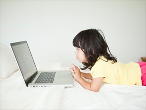 Girl lying down in bed, using laptop (4-5). Photo : Jessica Peterson