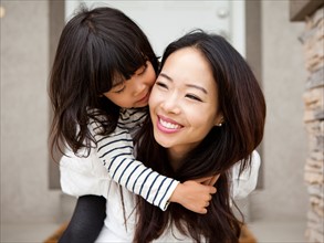 Smiling woman embracing by her daughter (4-5). Photo : Jessica Peterson