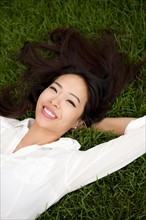 High angle view of smiling woman lying on lawn. Photo : Jessica Peterson